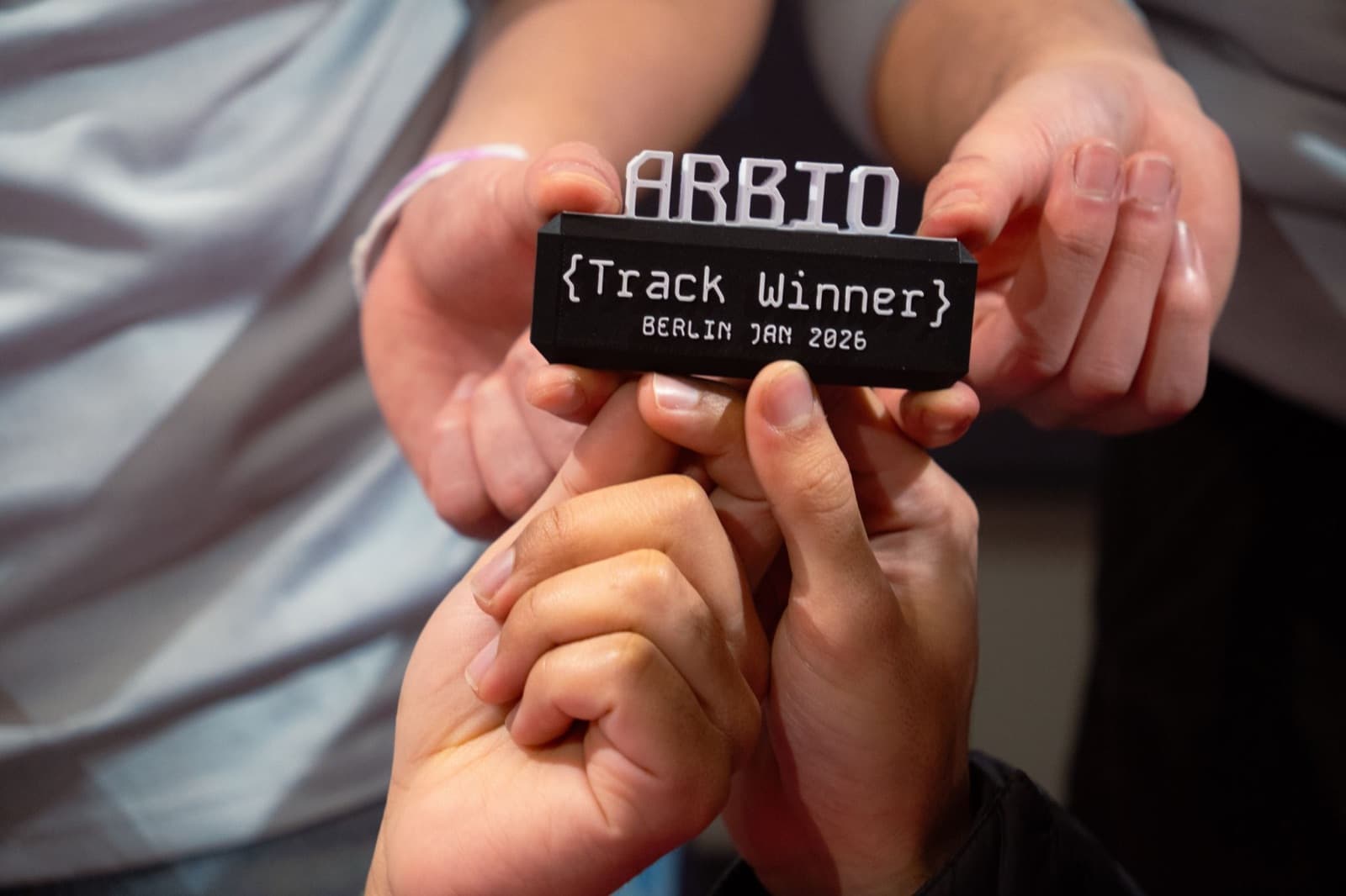 Close-up of a small 3D-printed token reading ARBIO {Track Winner} Berlin Jan 2026