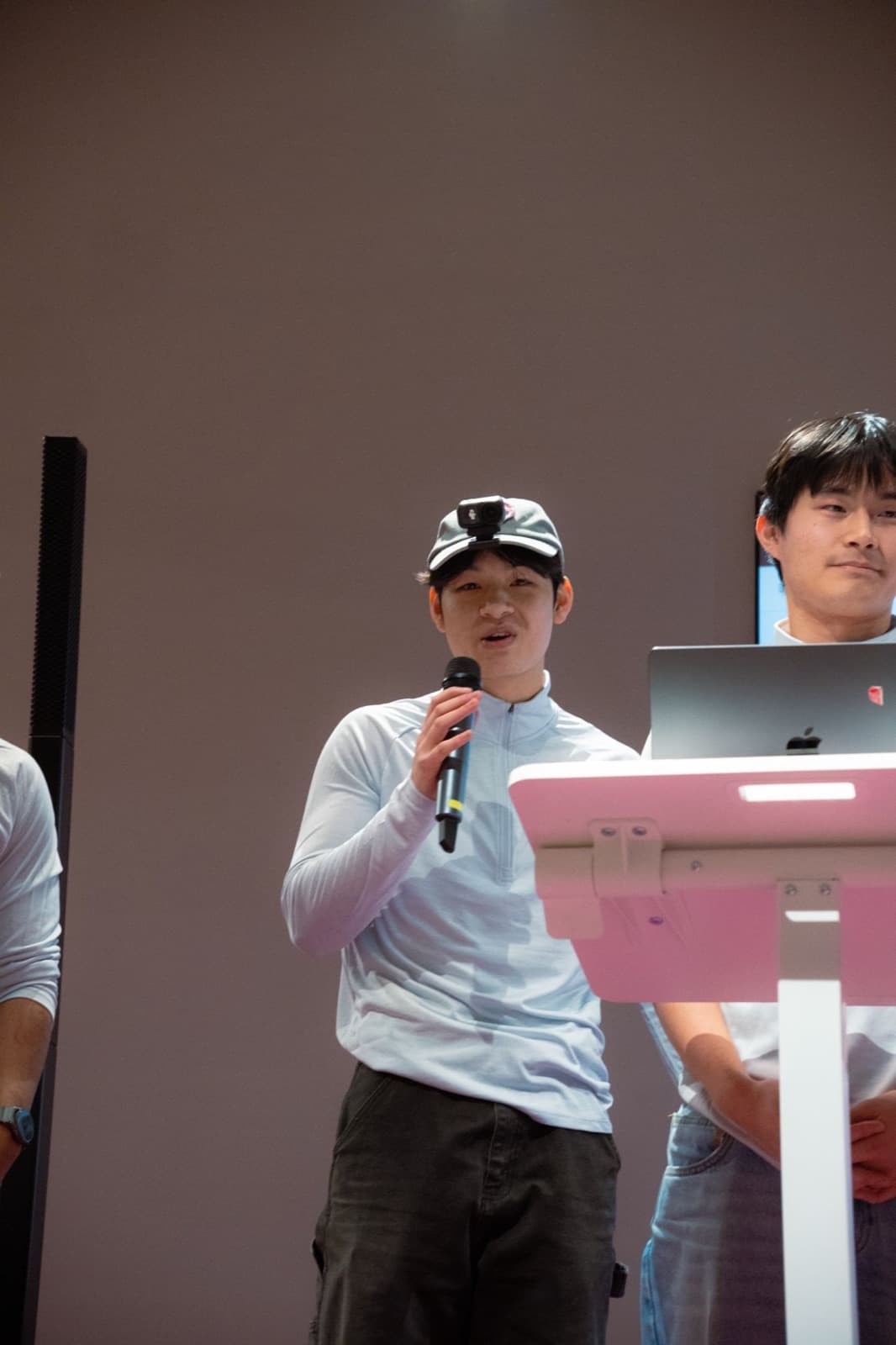 Nam pitching on stage with a microphone and a cap