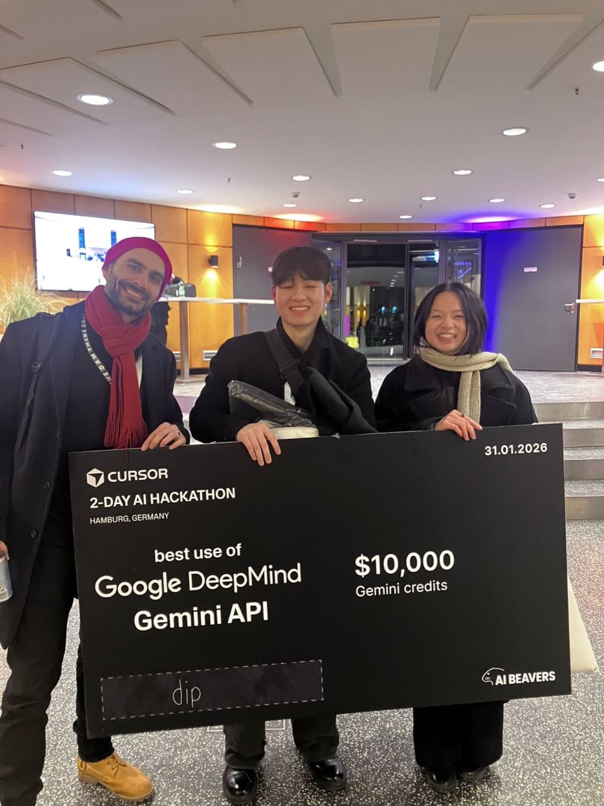 Three teammates holding the Cursor 2-day AI hackathon cheque for best use of Google DeepMind Gemini API, $10,000 credits