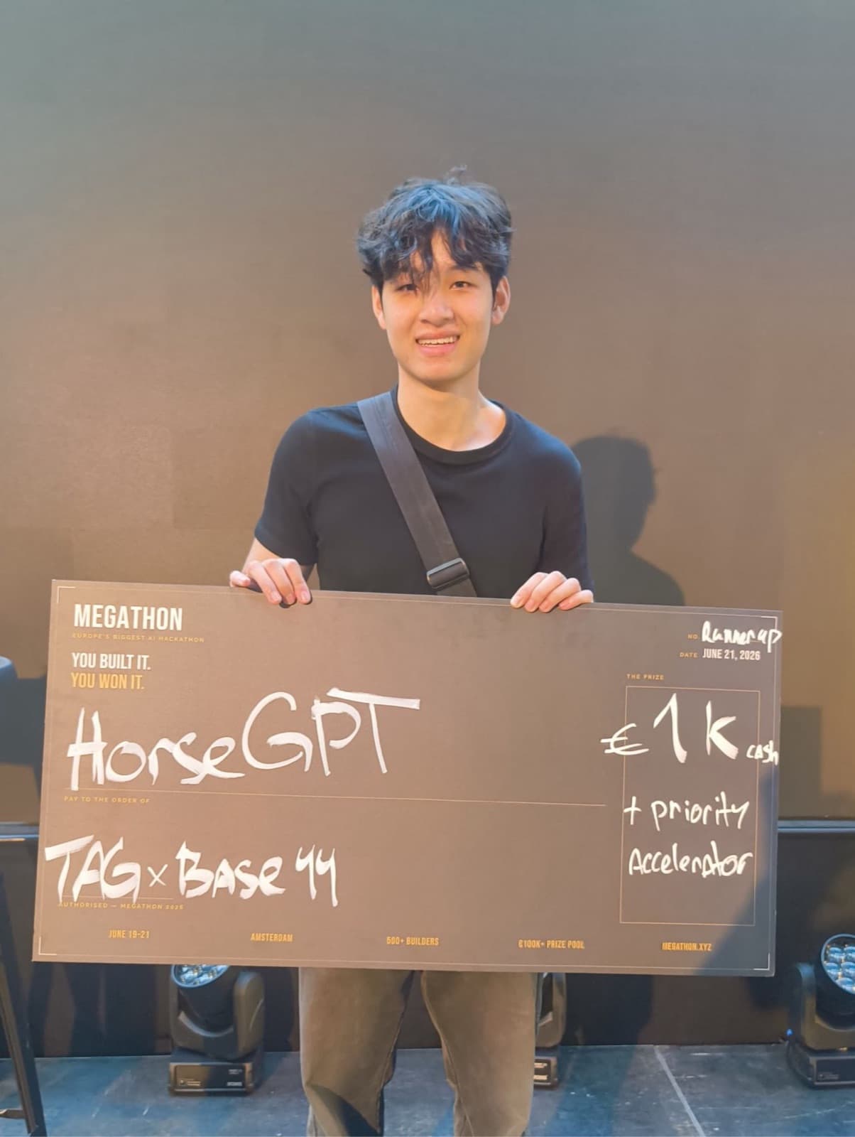 Nam holding an oversized Megathon cheque reading HorseGPT, TAG × Base44, €1k cash plus priority accelerator