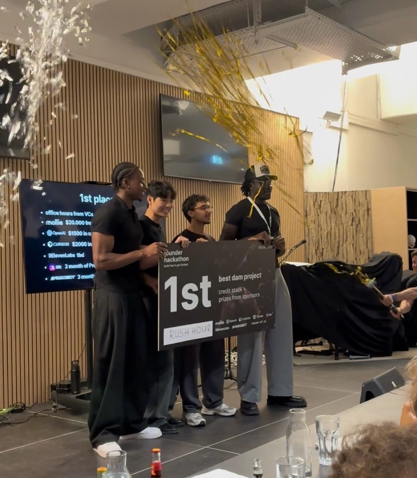 Team on stage holding the 1st place cheque while confetti falls